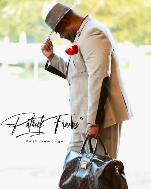 Patrick in a beige suit with a leather bag